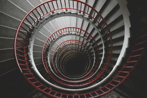 top view of a spiral concrete staircase with red railings
