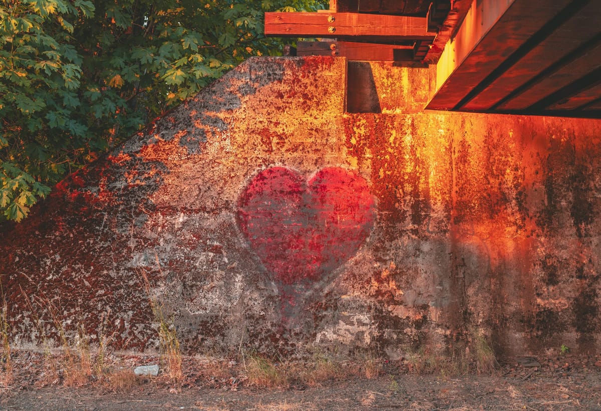 a red heart shape painted on a wall by the roadside