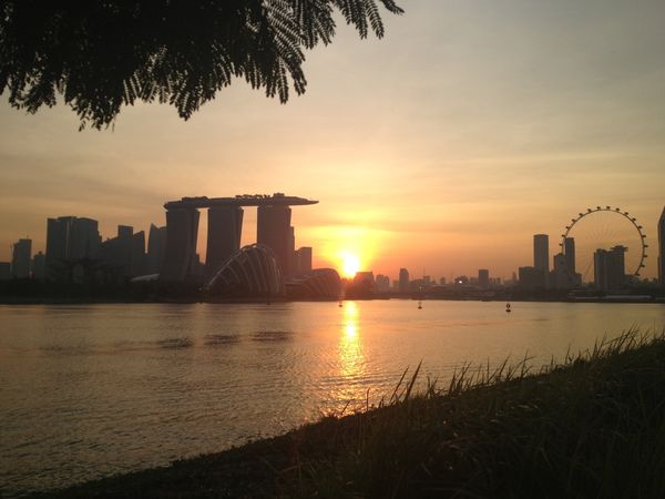 reflection in water of sun setting behind Marina Bay Sands