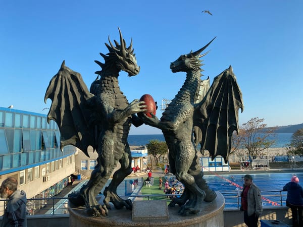 statues of two dragon standing facing each other and holding an egg