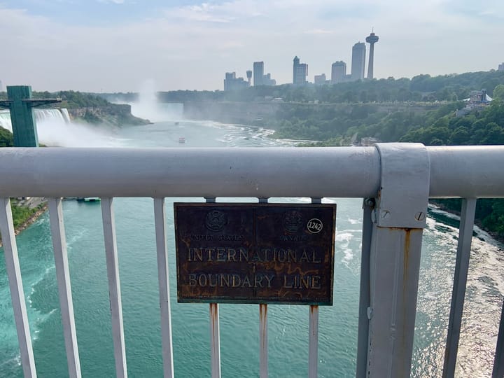 a signage on a bridge above a river that declares 'International Boundary Line'
