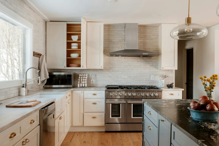 beautiful white kitchen with brass knobs and an island with a black marble countertop